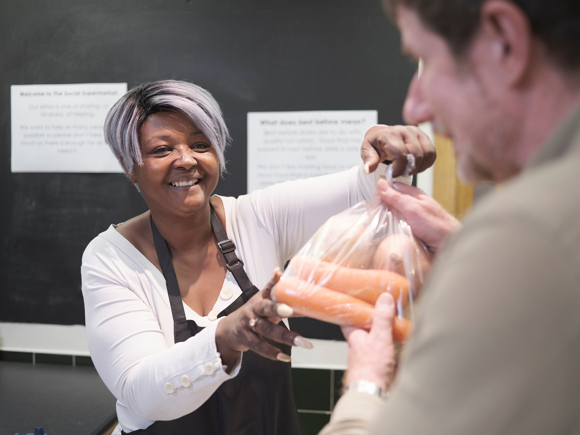 Women handing man a bag of carrots at a food dispensary