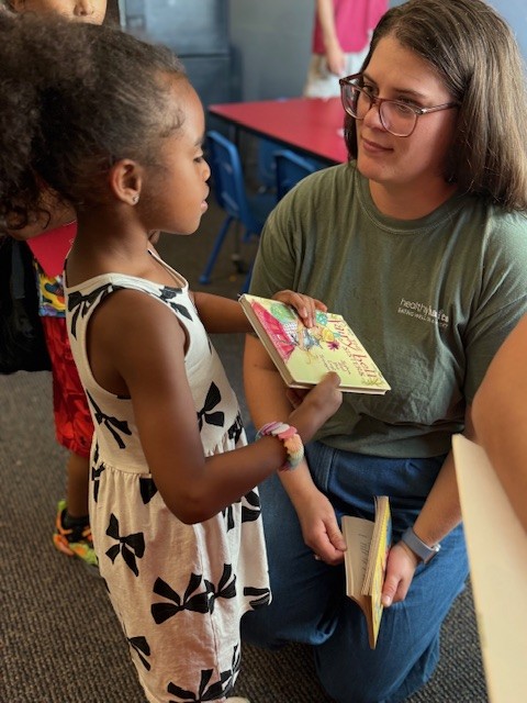 RI Food Bank Employee Flannery Sullivan chats with young friend at Books are Wings Kids Cafe event at the East Providence Boys & Girls Club