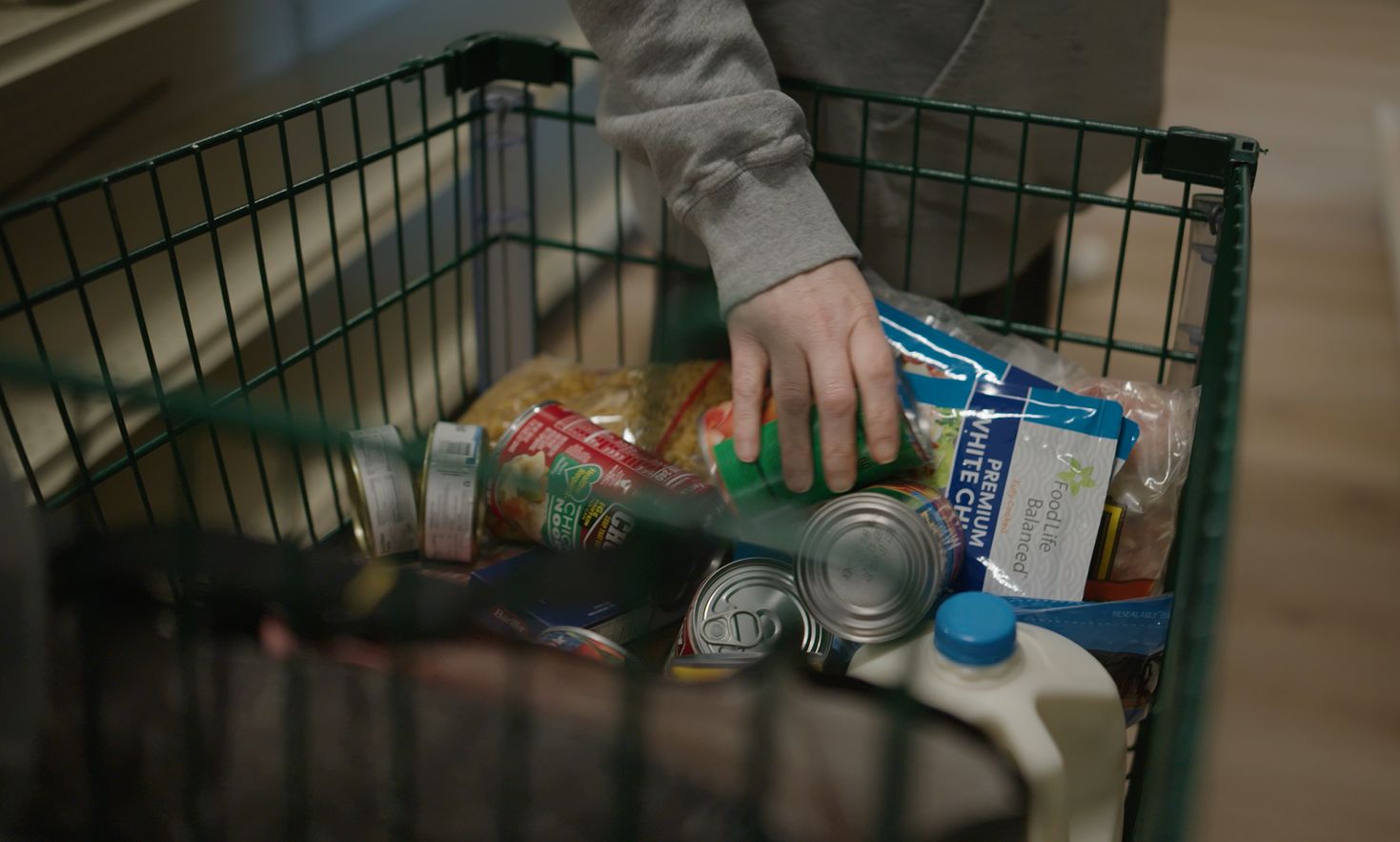 Hand reaching into a shopping cart at a food pantry.