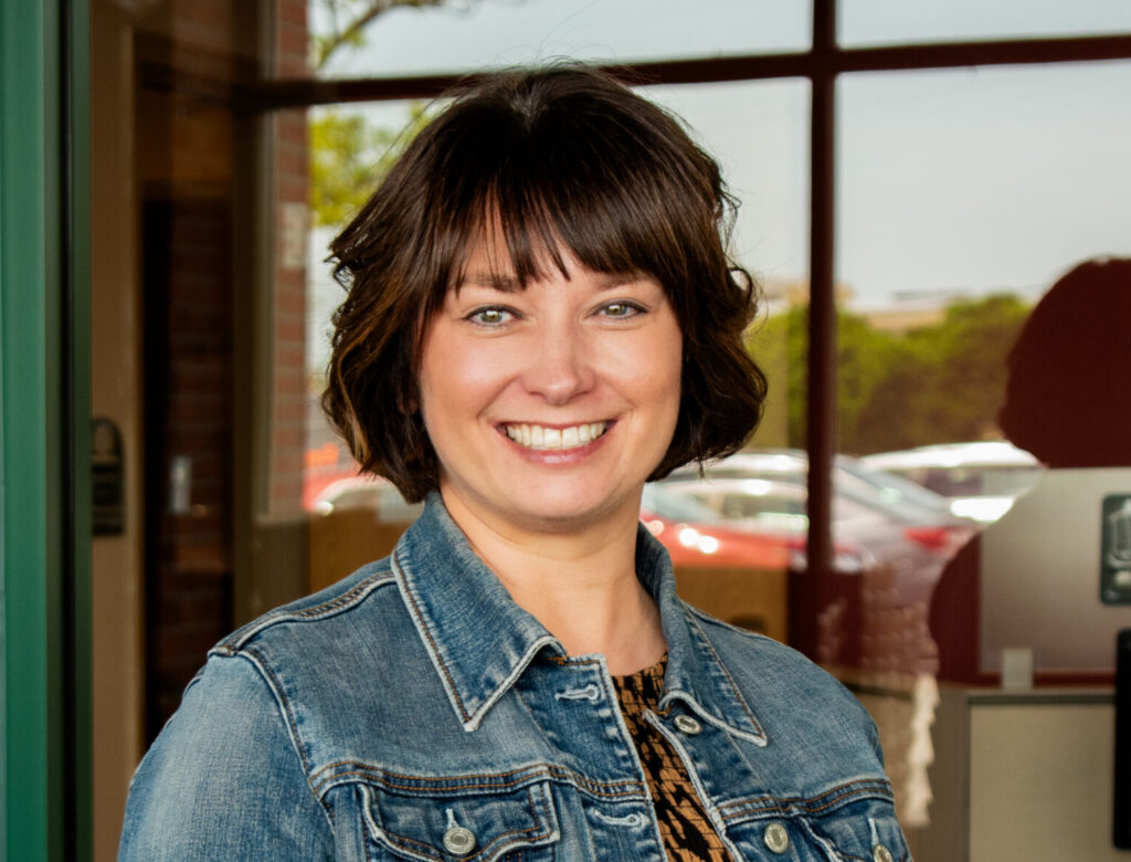 CEO of the RI Community Food Bank, Melissa Cherney, smiles in an outdoor setting.